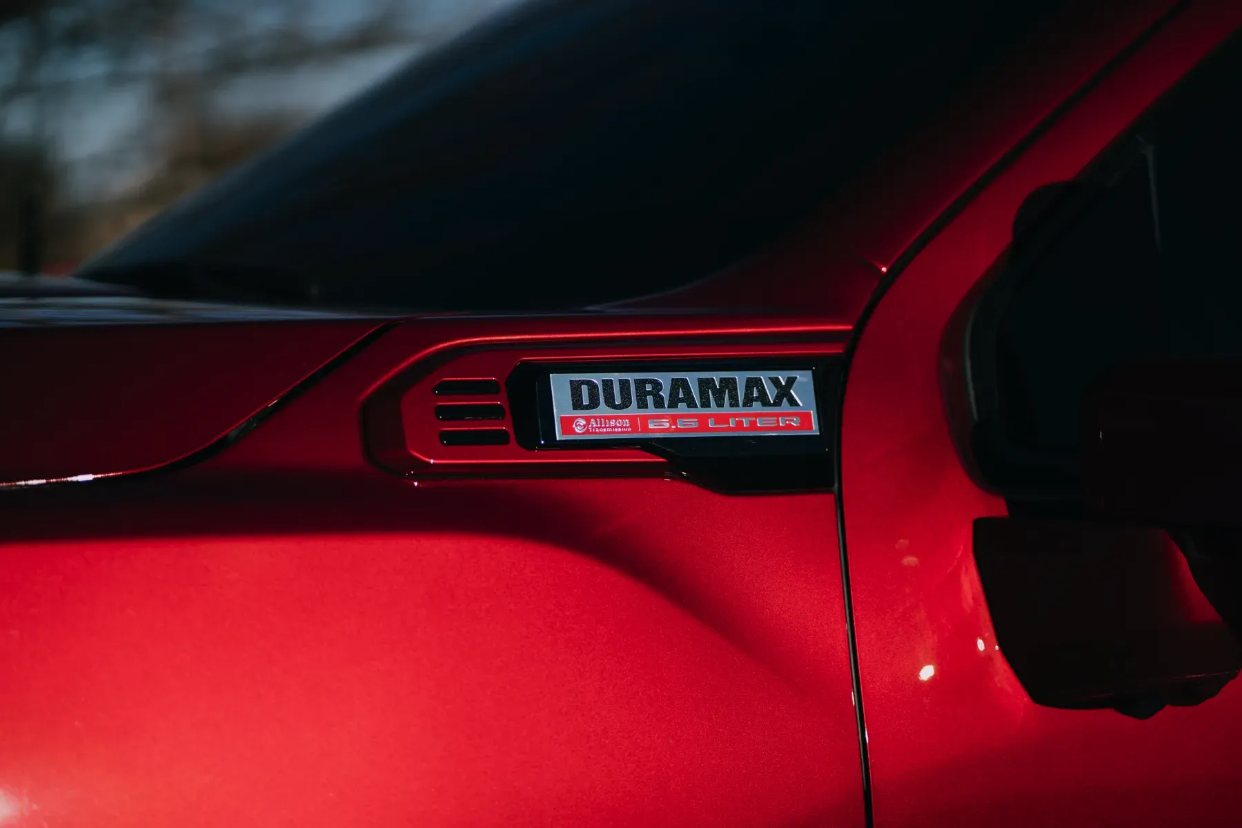 Close-up of a red truck with a "DURAMAX TURBO DIESEL" badge on the fender.
