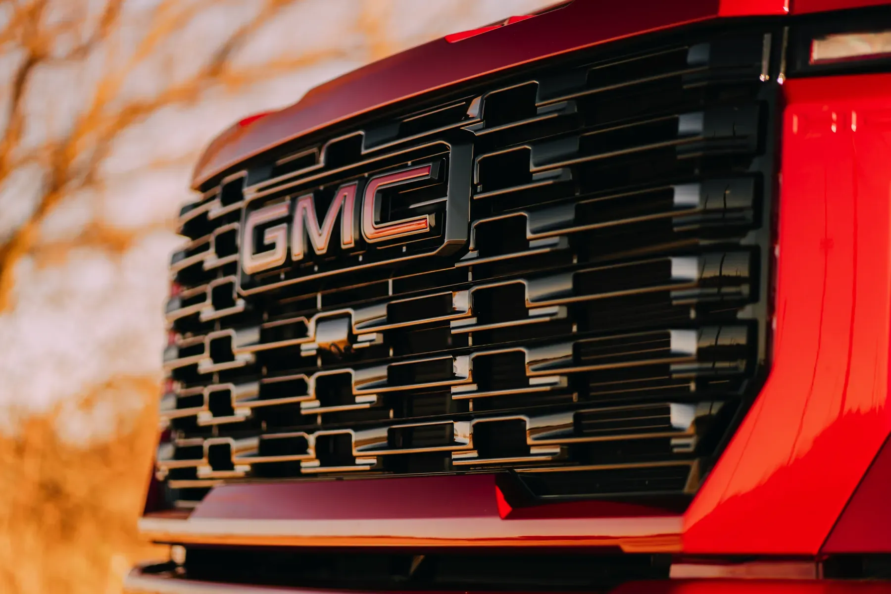 Close-up of a red GMC truck's grille with the GMC logo prominently displayed.