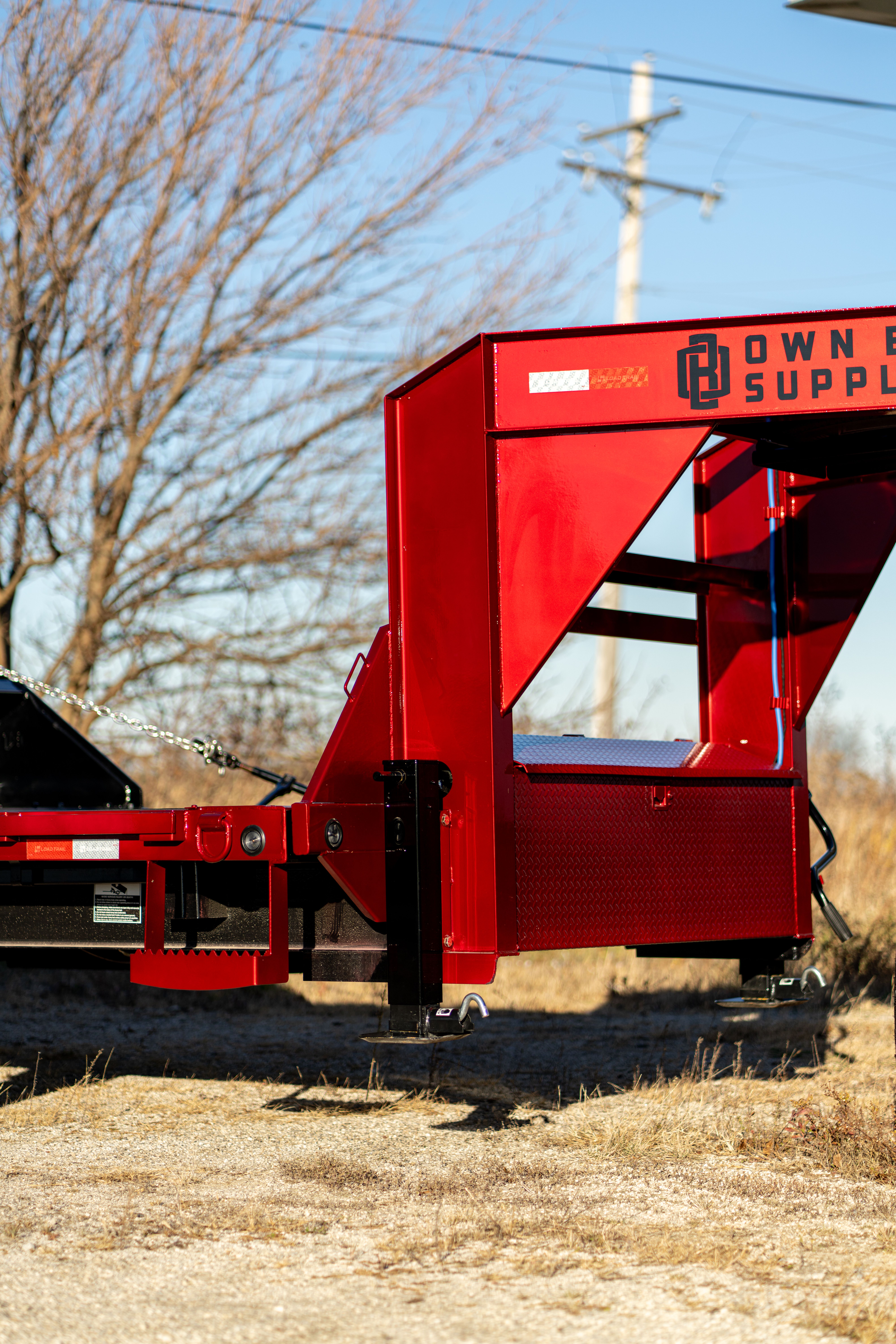 Bright red Town & Country Supply gooseneck trailer parked outdoors.