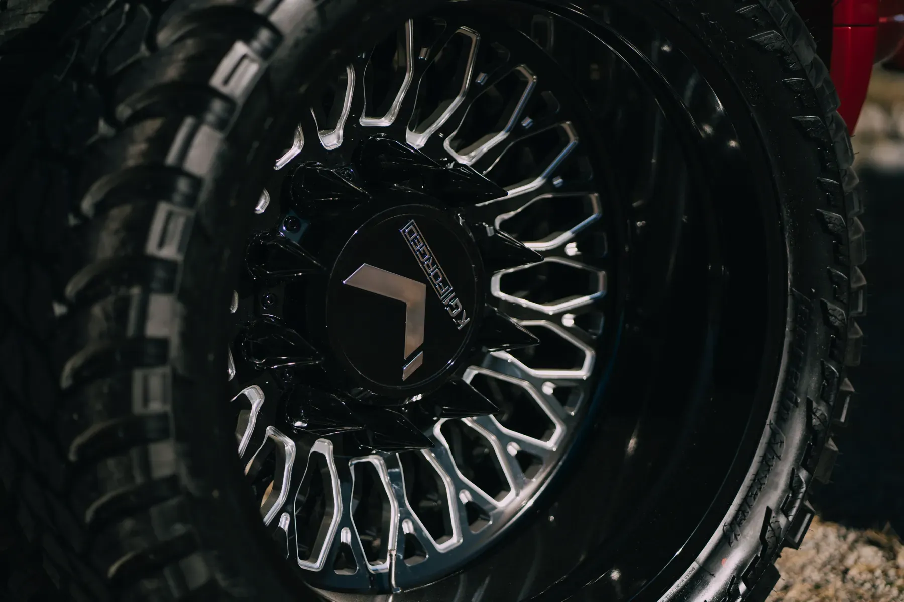 Close-up of a custom black off-road truck wheel with silver accents and aggressive tire tread.