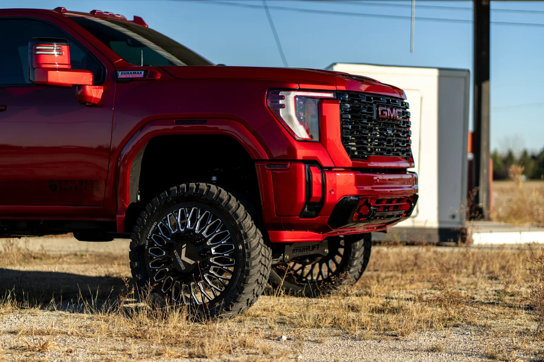 Red GMC Sierra pickup truck with custom black and chrome wheels parked outdoors.