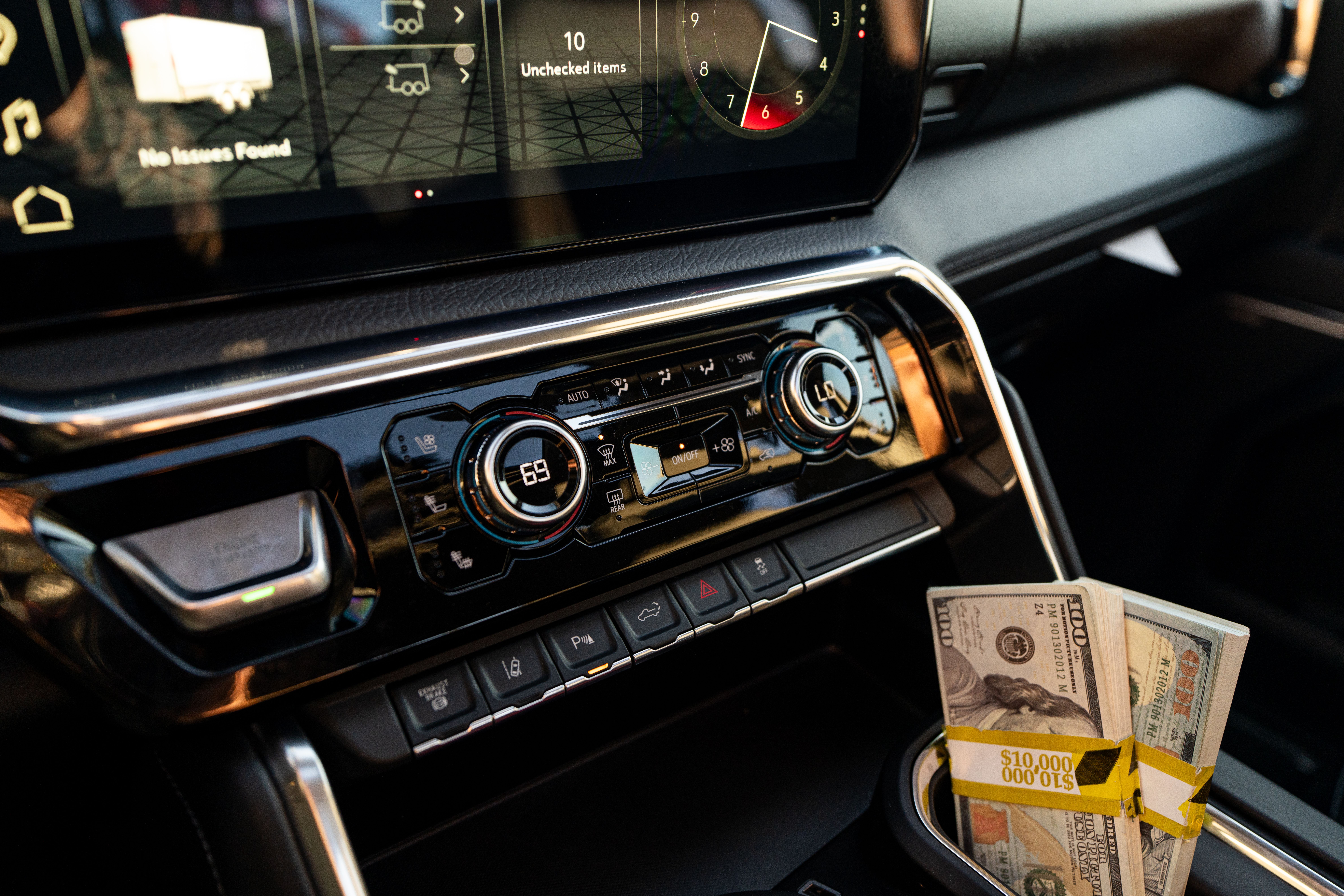 Close-up of a modern car interior with stacks of cash in the central cup holder.