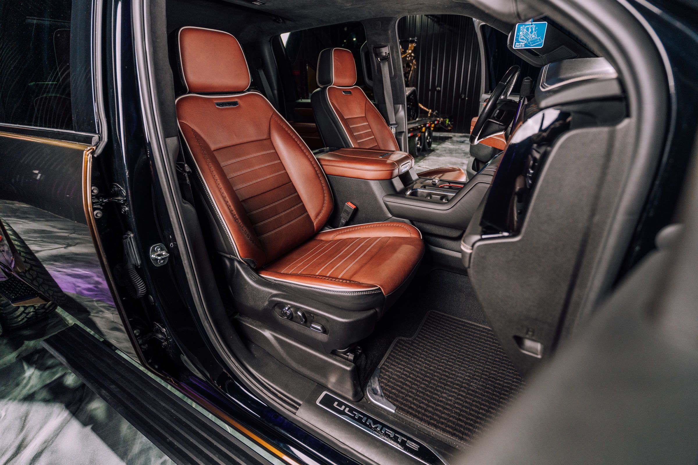 Luxurious dark car interior showcasing two brown leather front seats with ribbed design.