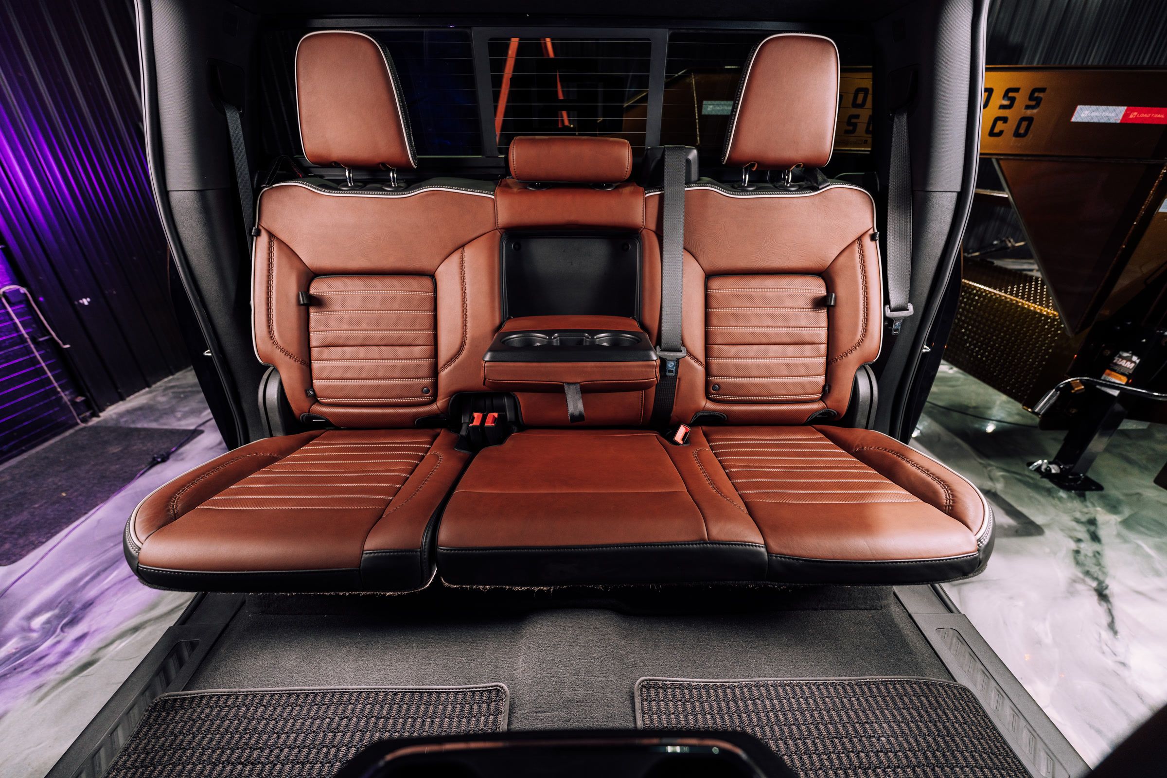 Spacious brown leather rear seats of a truck featuring a central fold-down armrest.